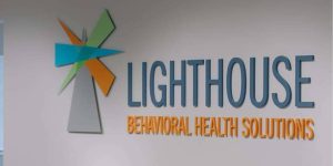lighthouse-behavioral-health-corporate-hq Lighthouse Behavioral Health Solutions logo displayed on a wall.