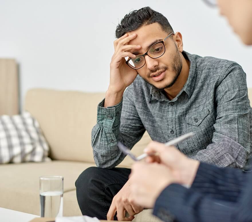 stressed-man-therapy-session Man showing signs of stress while talking with a therapist