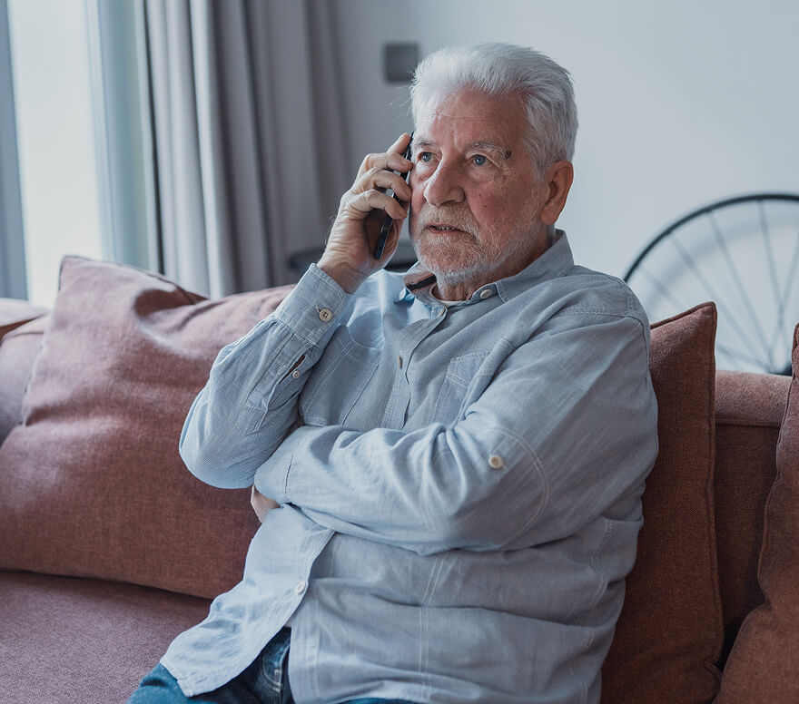 when-to-choose-clinic Older man sitting on a couch talking on the phone.
